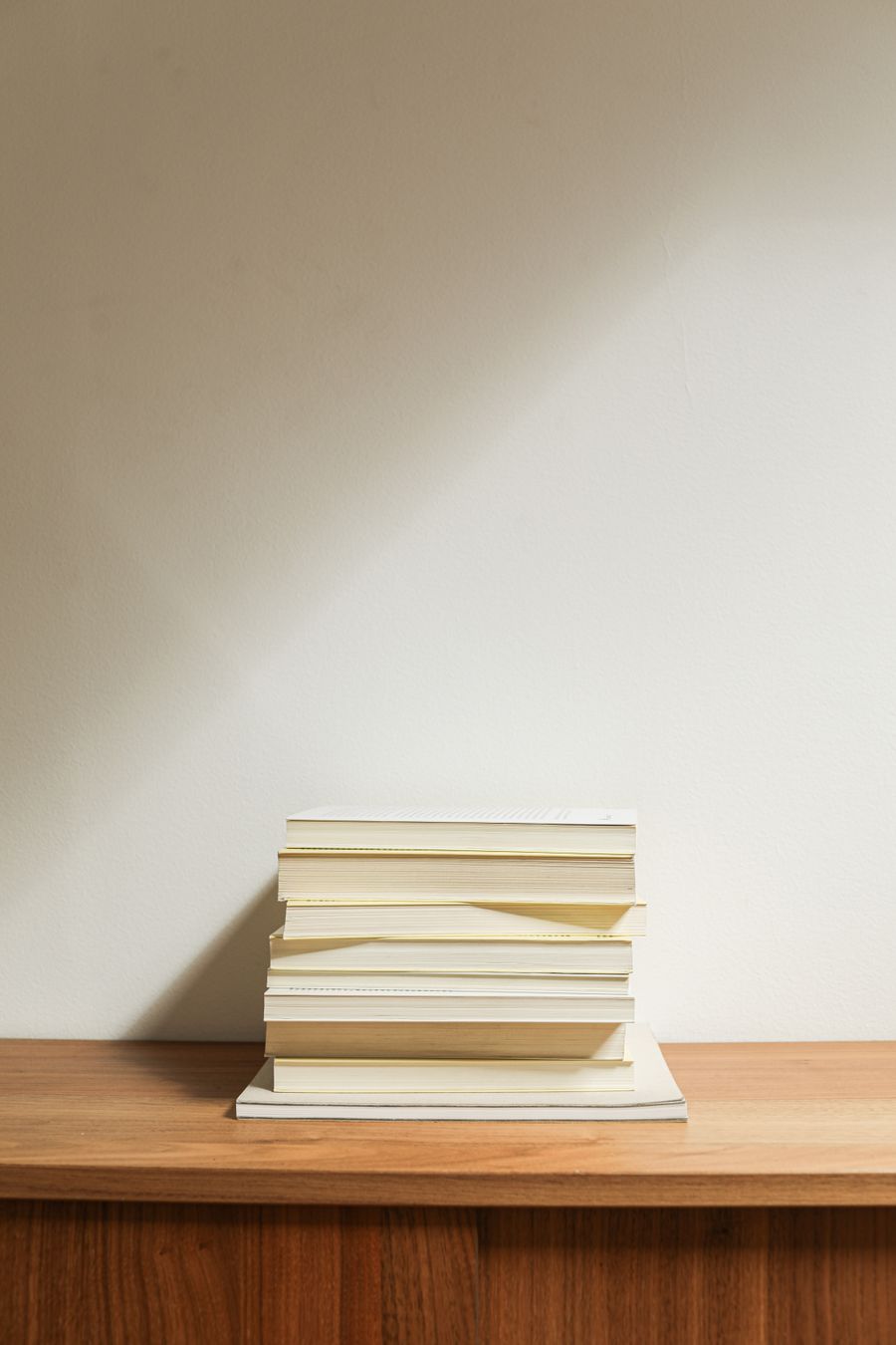 Neat stack of finished paperback books on a wooden desk
